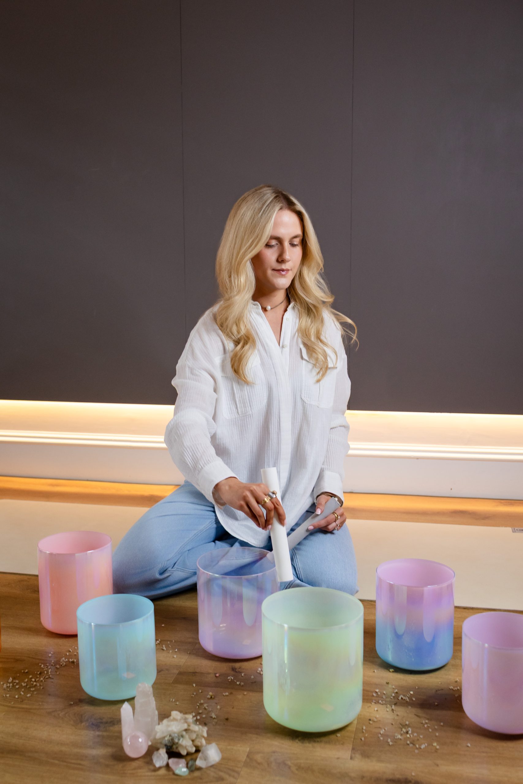 Woman playing crystal singing bowls for sound healing therapy