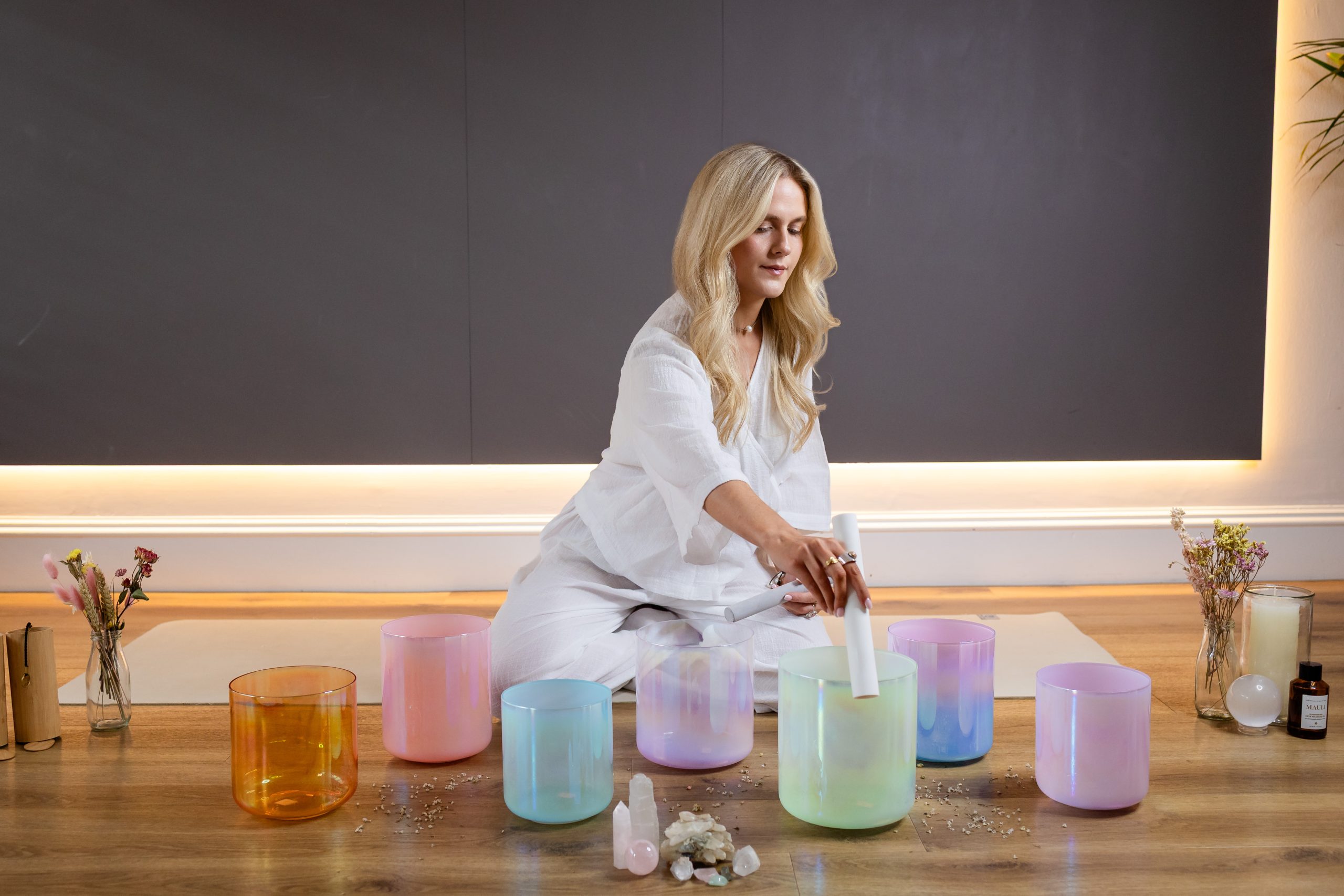 Woman playing crystal singing bowls in a serene meditation space