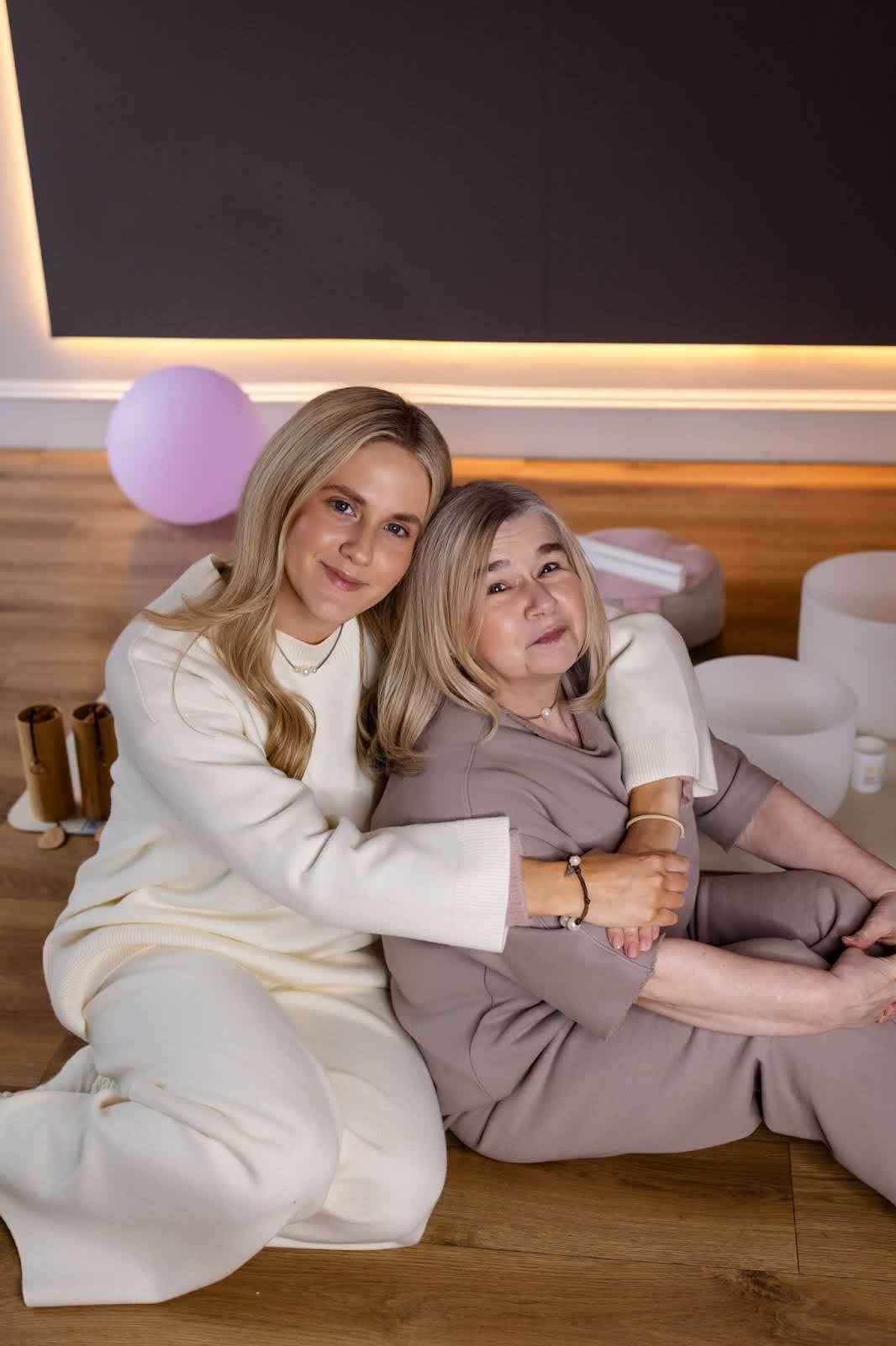 Two women sitting on the floor with smiles and mutual affection