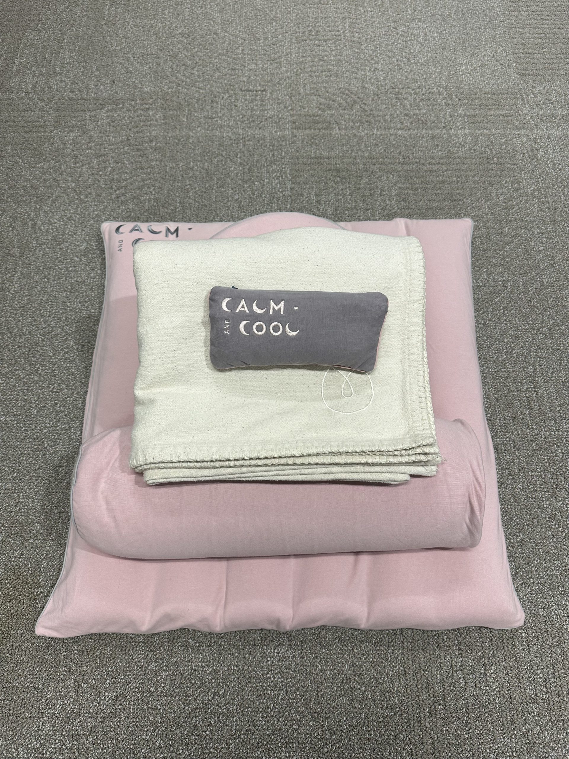 Folded blankets and pillow with calm and cool design on carpet