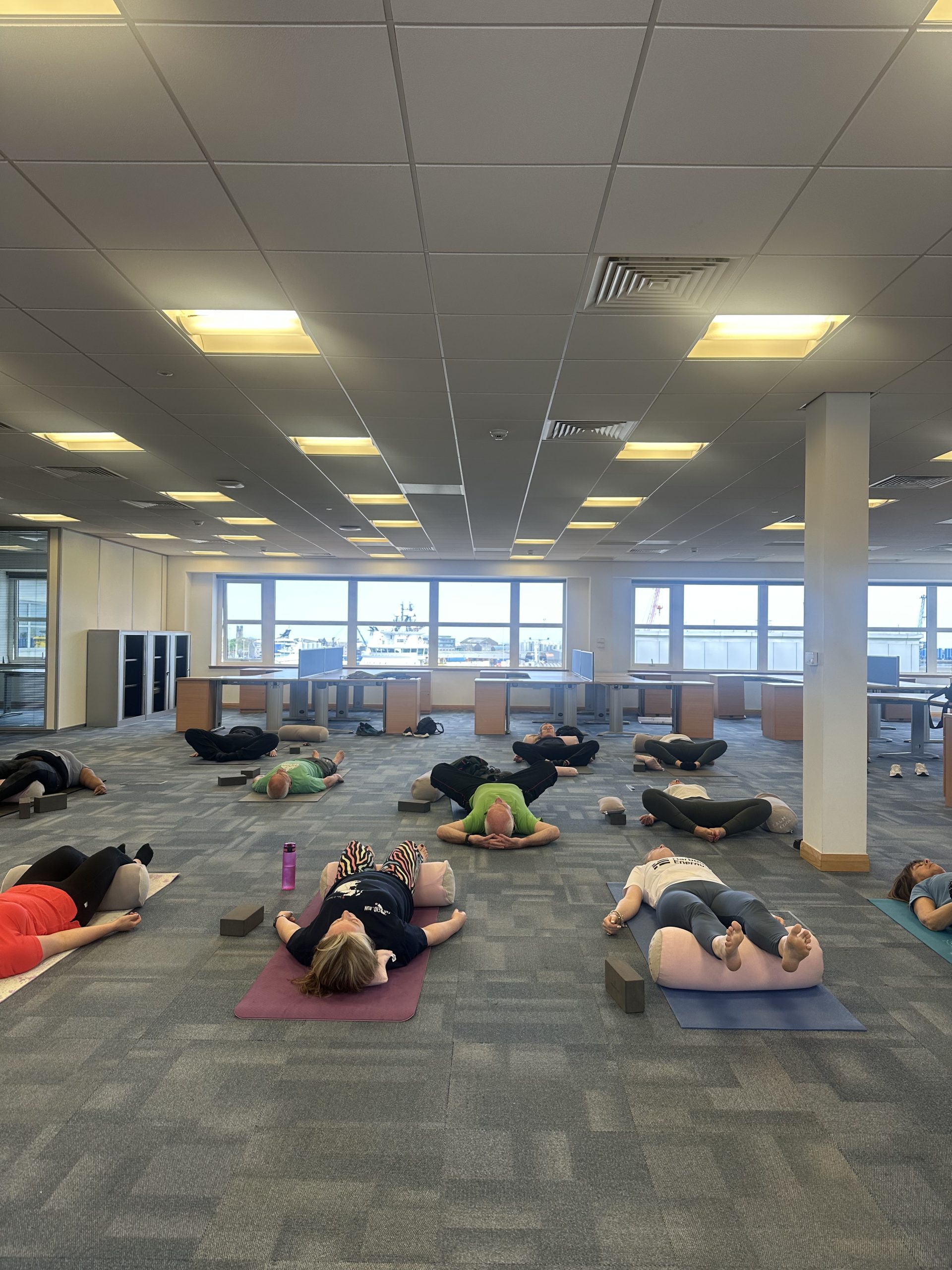 People practicing yoga in a spacious well-lit office setting