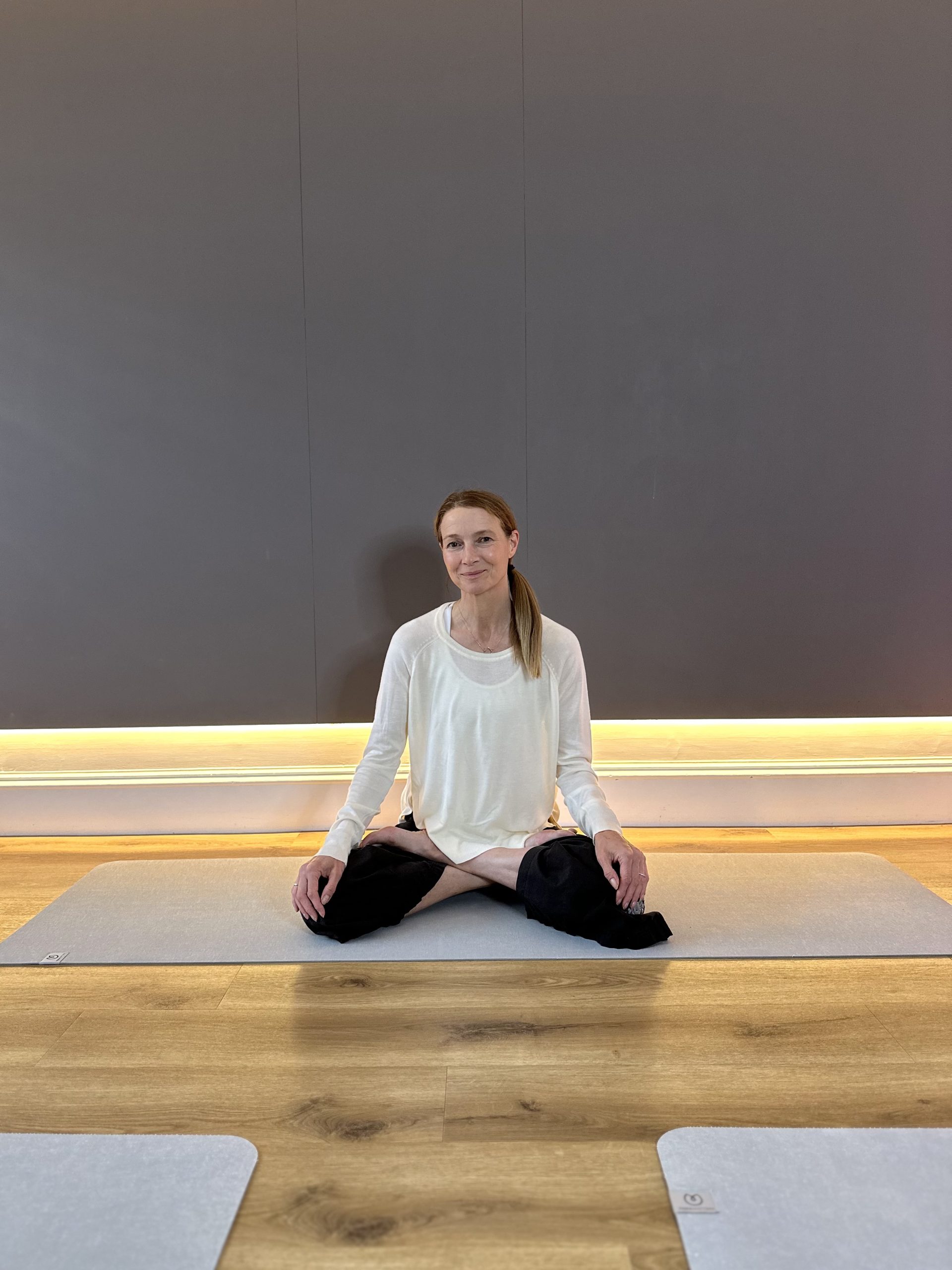 Person practicing meditation on yoga mat in serene studio